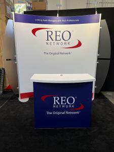 RENTAL: 10 x 10 Curved Gravitee System Design with (3) LED Arm Lights, RE-1558 Reception Counter with White Laminated Top, (2) Frosted Acrylic Accent Wings, and SEG Fabric Graphics.